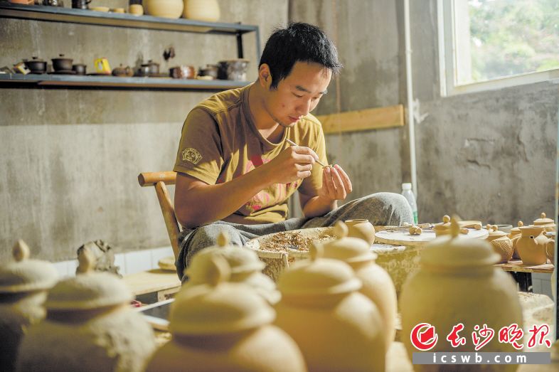 1993年出生的刘嘉豪是铜官“泥人刘”第四代传承人，大学毕业后，他回到了铜官，接过了祖辈的雕刻刀。宽敞的工作室内，刘嘉豪打磨着一个茶壶的泥胚。