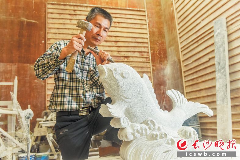 石山脚下，47岁的周旭正在雕刻一座佛像，这里不但是他的厂房，同时也是丁字湾街道农民麻石雕刻免费培训基地。