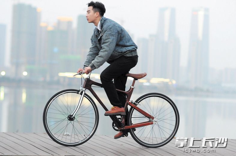 杨洋骑着自己设计制造的花梨木自行车，在创业创新的道路上一路疾驰。 受访者 供图