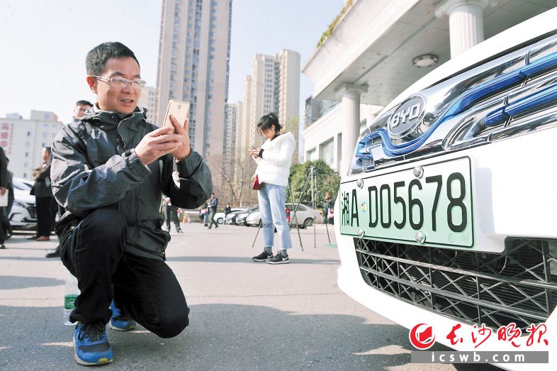 湖南省首副新能源汽车专用号牌车主兴奋不已，掏出手机拍照留念。长沙晚报记者 小刘军 摄