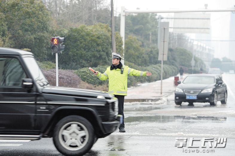③昨日傍晚，冰雪清理后，花侯路长沙大道路口车流量增加，雨花交警大队十三中队辅警李思平在疏导交通。 长沙晚报记者 余劭劼 摄