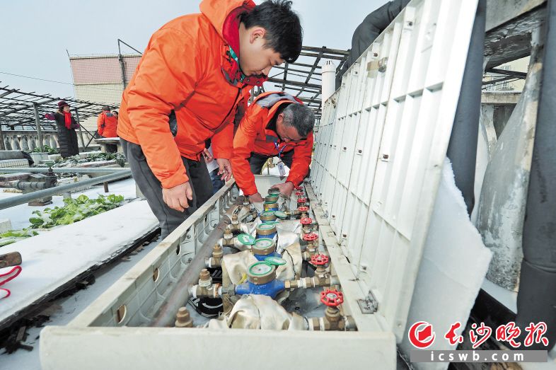 昨日在岳麓区航空母舰小区，长沙供水公司工作人员在帮住户免费更换冻坏的水表。 长沙晚报记者 王志伟 摄