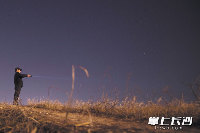 夜幕降临后，黄健雄拿着手电筒沿着高铁护栏一路巡查。