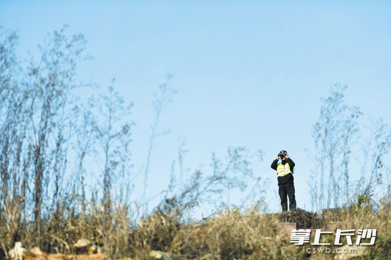 黄健雄在用望远镜进行瞭望观察，防止有人闯进高铁线路。