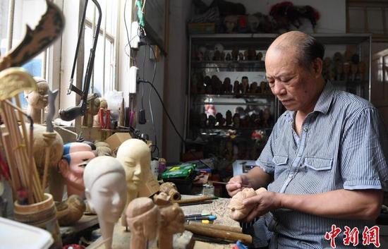 图为杨亚州在其工作室雕刻木偶头。