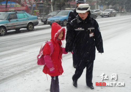 交警冒雪牵引上学学生平安过马路
