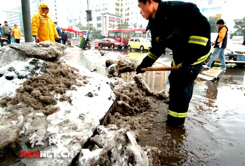 一位消防武警战士在清除堵塞了下水道口的积雪