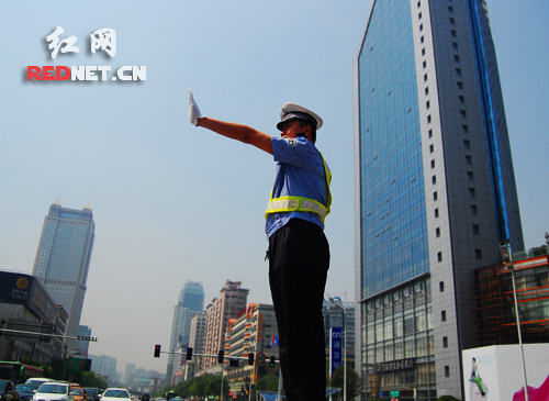 在长沙市主干道芙蓉中路,交警正在指挥流水般的车龙有序前行。