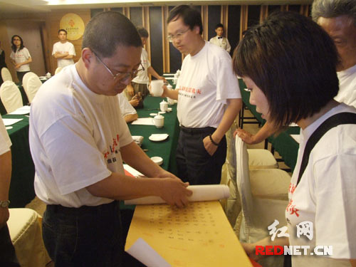 书法家刘建军(左)向义卖活动组委会交送长达2米的书法作品《千字文》。