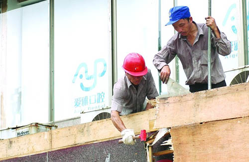 6月30日上午,长沙市芙蓉中路,两名工人正在拆除爱雅口腔医院墙外的广告牌。记者 田超/摄