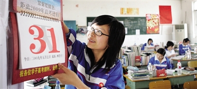 昨日，长沙市稻田中学高三教室内，一名女同学将距离高考还有31天的提示牌挂到墙壁上。图/记者殷建军
