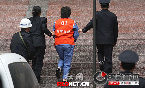 (开庭前身穿1号囚衣的谢才萍被法警押进法庭受审.图/广州日报)