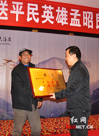 湖南张家界市委宣传部长肖凌之（右）为孟昭良（左）授予“平民英雄、道德模范”荣誉牌匾。