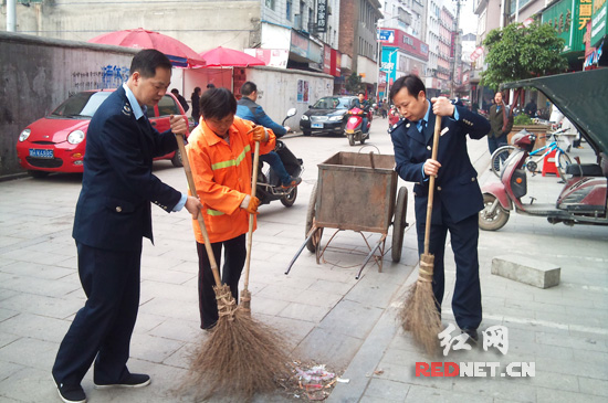 图为该局青年干部与环卫工人在街道上打扫卫生的现场。