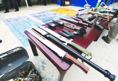 麻城市公安局缴获的犯罪团伙使用的各种管制刀具、钢叉及自制手枪等作案工具以及涉案的大量车牌。