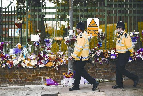 24日，伦敦民众在22日恐怖杀人案现场放置鲜花，悼念被害的英军士兵。