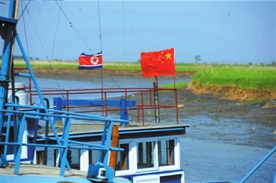 5月23日,在丹东东港附近的鸭绿江支流处,不少渔船都悬挂了中国与朝鲜的两国国旗。京华时报记者王苡萱摄