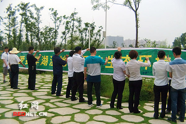 长沙洋湖湿地公园工作人员和游客纷纷在“保护生态环境”的宣传横幅上签下自己的名字，表达关爱家园，保护环境的决心。