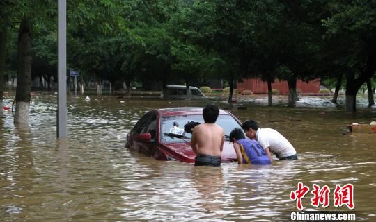 图为一辆汽车在柳州市滨江路被快速上涨的洪水围困，车主尝试将车辆推行撤离。 蒙鸣明 摄