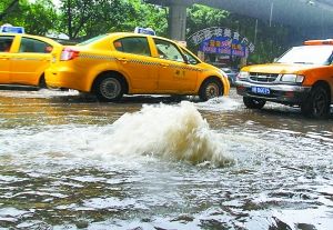 昨日上午，因为下水道排水不畅，长滨路的窨井盖被掀翻，雨水倒灌路面。 重庆晨报记者 罗伟 摄