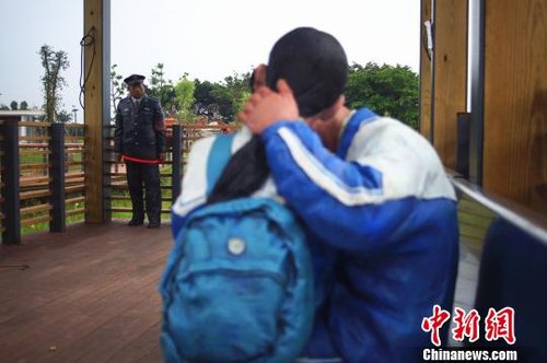 一名身着警服的“男子”直勾勾地盯着“中学生”情侣。 王欣 摄