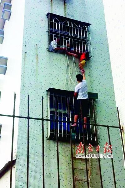 3岁的小可不慎失足,被卡在防盗网中间。住在对面5楼的欧先生上演了“托举哥”的义举。南方日报记者 胡国球 摄
