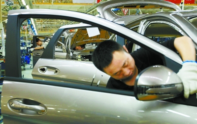 6月29日,北京汽车株洲分公司总装车间内,工人正在自动化流水线上安装汽车部件。本报记者刘尚文摄