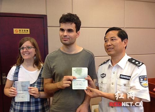 图：湖南省公安厅副厅长谭和平（右一）现场颁发了新法实施后的第一本外国人居留证。