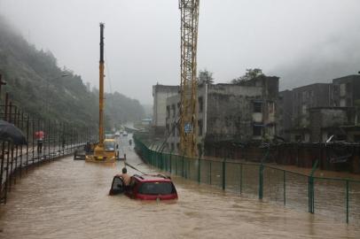 6月30日,北川老县城一男子雨中推车前行。