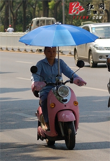 天气炎热 摩托,电动车"打伞"上街现象增多