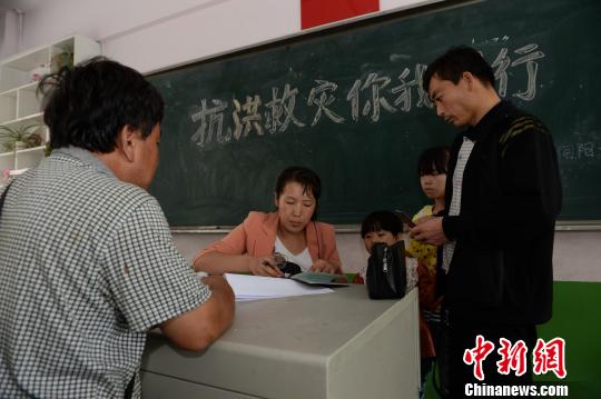 转移民众在延安宝塔区东关小学安置点进行登记。　张一辰　摄