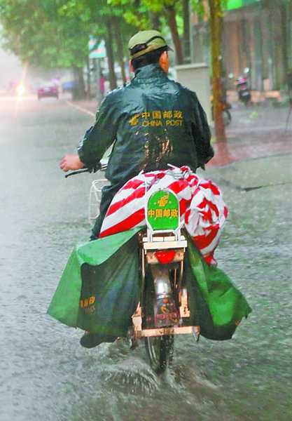 中国邮政的投递员在雨中骑行