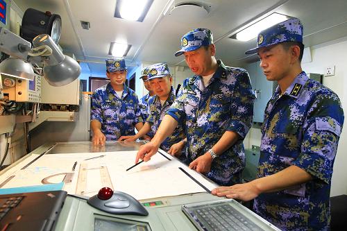 8月22日，海军舰艇编队指挥员魏钢少将（右二）在青岛舰海图室布署编队航行计划。新华社记者 查春明 摄