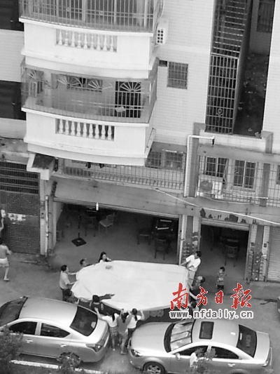 街坊们合力撑开救人的垫子。