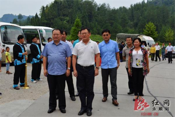 图为县委书记李平陪同朱建纲(前排右一)考察老司城,在拦门酒仪式现场.