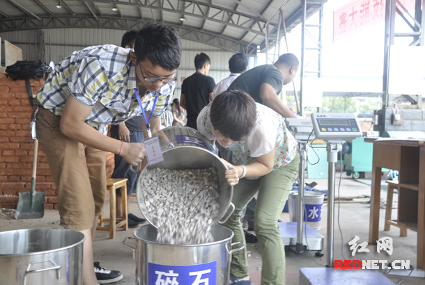 参赛女选手提起整桶的碎石准备加工成混凝土。