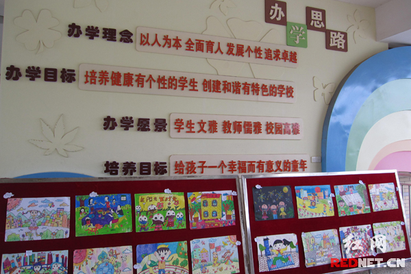 学生的绘画作品摆在校园文化墙边展览。