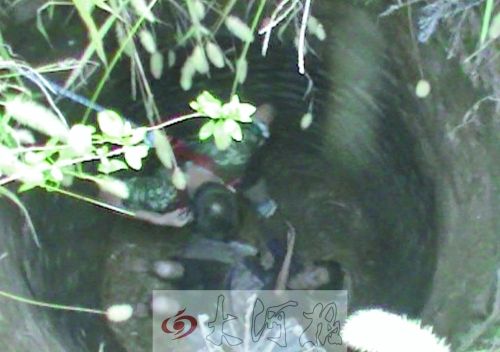 女子仰面躺在井底，消防员进入井中施救。