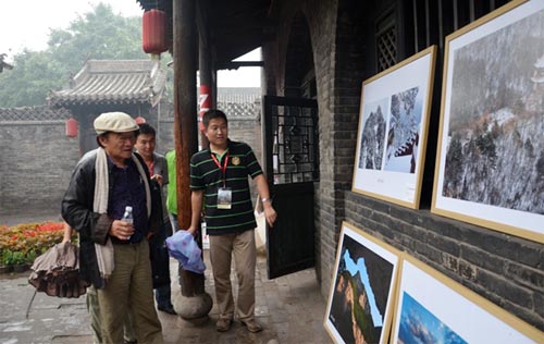 中国摄影家协会副主席、2013平遥国摄影大展评委会主席朱宪民(左一)参观石膏山摄影作品展。