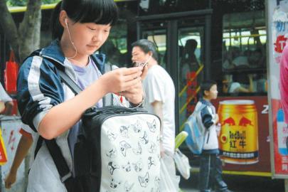 达州市第一中学大门外低头玩手机的学生。