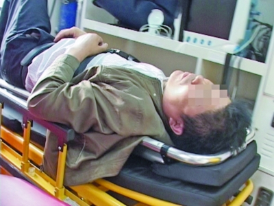 大图：从5楼摔至2楼顶棚的男子被抬上担架抢救。