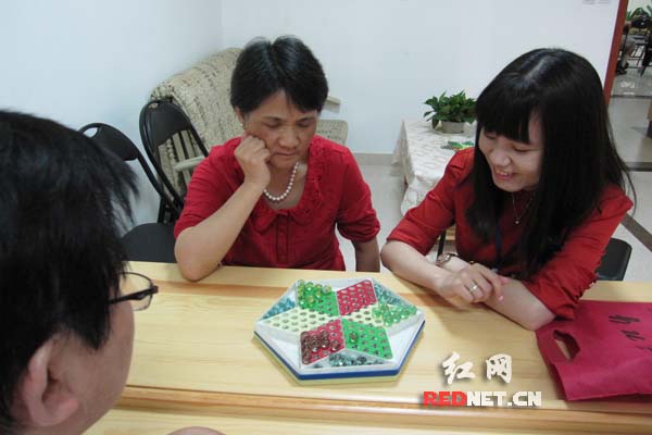 银谷国际社区工作人员陪老年人下跳棋。