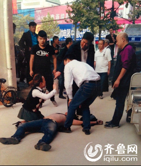 网友提供的现场图片，被打商户王某倒在地上，王某的姐姐跪在旁边。