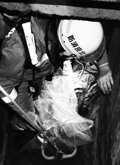 消防员正准备使用塑料袋下地窖包裹男尸 以便用担架抬出。刘新