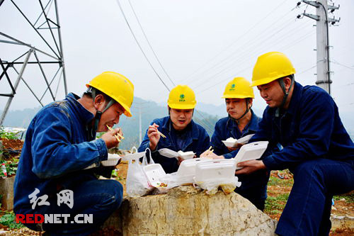 电力工人在工地上吃盒饭。