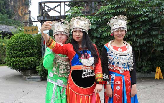 10月23日，采访团的美女记者在明仕田园身着少数民族服装体验民族风情。）