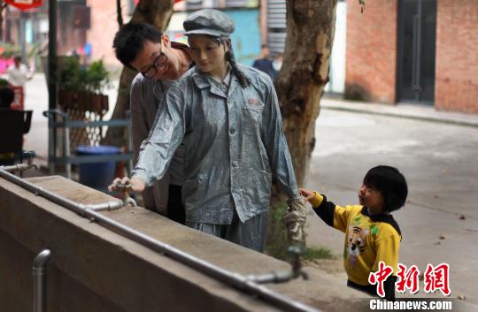 10月25日，在成都一处文化创意园区内的街道上，一尊开水龙头的姑娘雕塑吸引着过往市民的目光，惟妙惟肖的表情和动作仿佛真人一般令人驻足。中新社发 泱波 摄