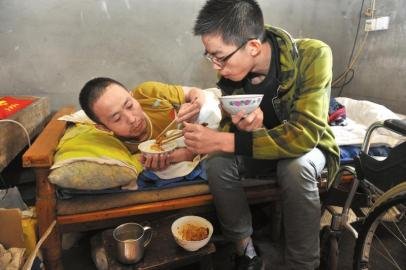 17岁男孩为照顾瘫痪父亲 背着爸爸上学