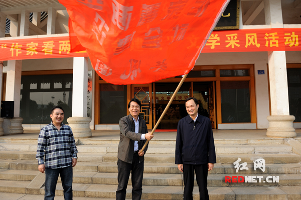 中国作协党组成员、副主席、书记处书记何建明(中)和湖南省委常委、长株潭试验区工委书记、管委会主任张文雄(右)向采风团代表王跃文授旗。