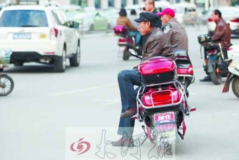 郑州街头，多辆“摩的”在路口等客。